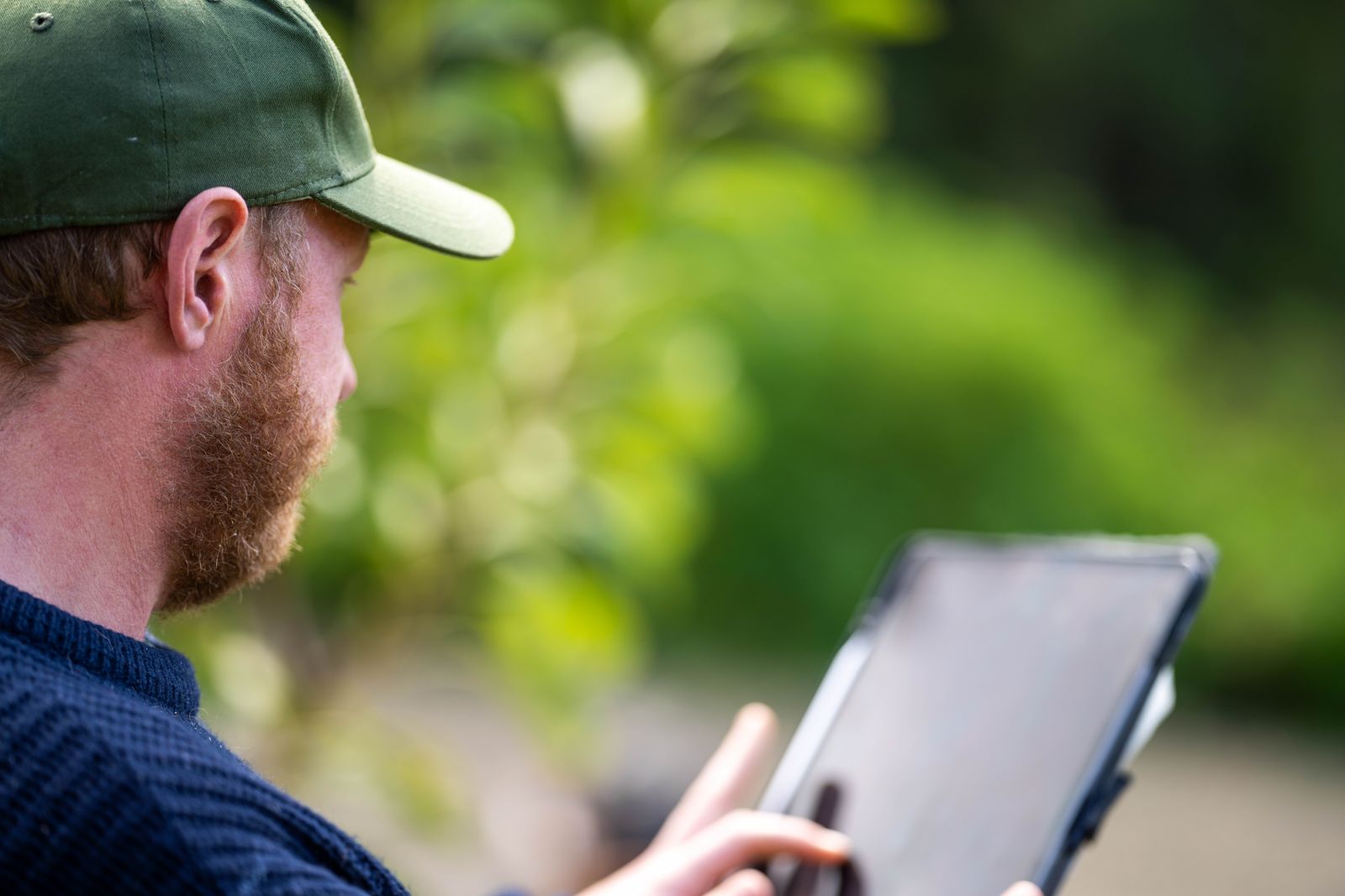 A landholder reading a report on a tablet outdoors